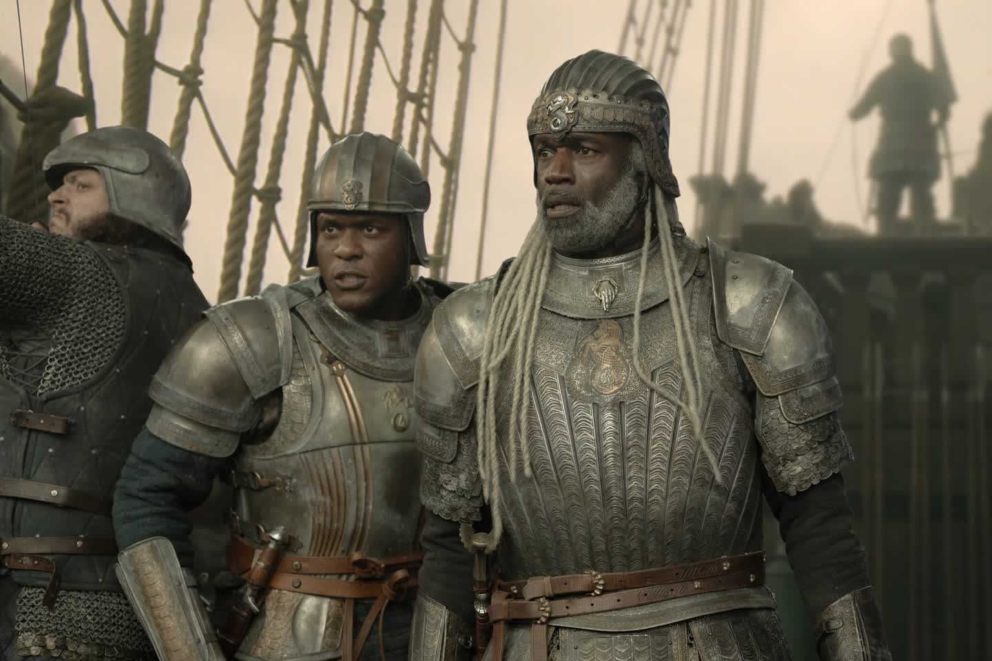 Three Armored Warriors on a Ship Deck with Ropes and Sails Behind Them Looking Ahead