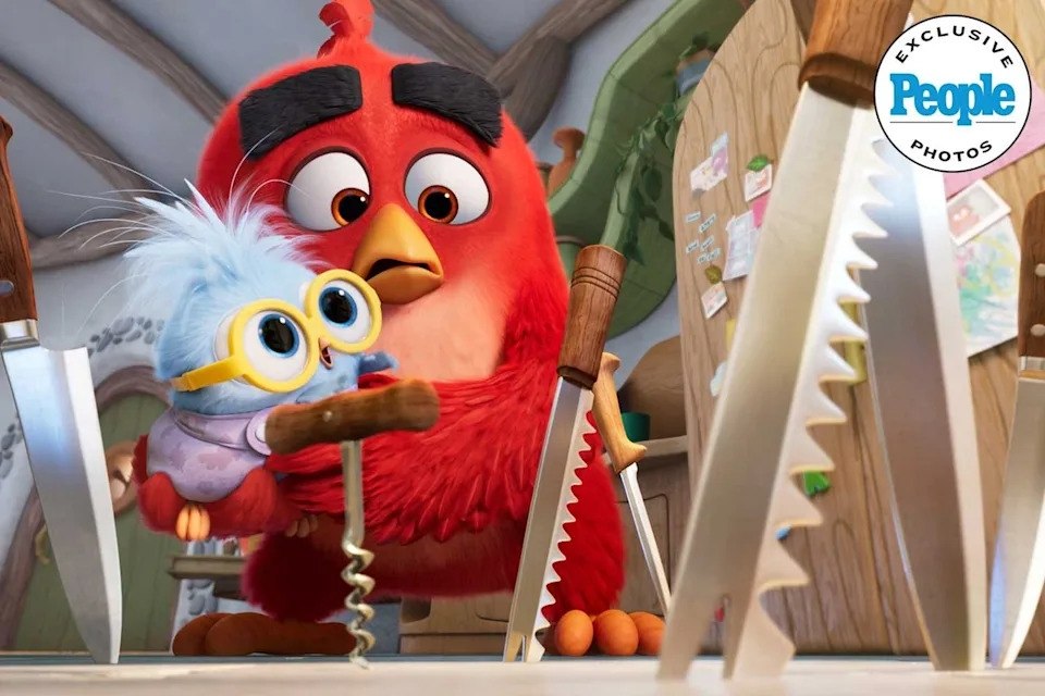 Animated Red Bird and a Small Blue Bird Wearing Yellow Goggles Hiding Behind Large Saw Blades in a Cluttered Workshop Scene