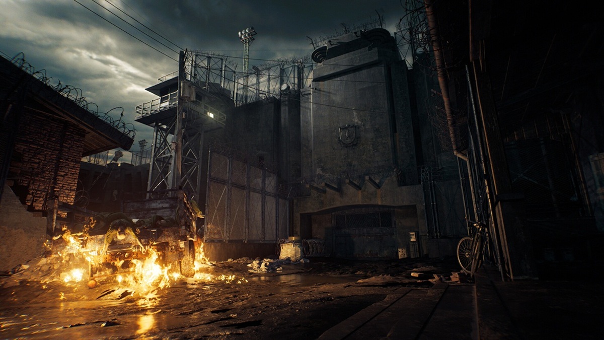 Resident evil veronica 03 Dark Fortified Complex with Barbed Wire Fencing and a Burning Debris strewn Foreground Under a Stormy Sky Bicycle Against a Wall on the Right