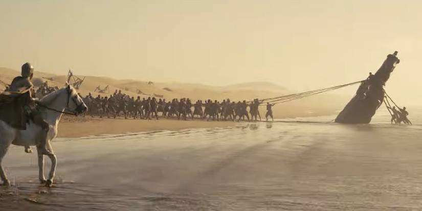 1000050781 Group of People Pull a Large Shipwreck Toward Shore Across Shallow Water with a Rider on a Horse in the Foreground