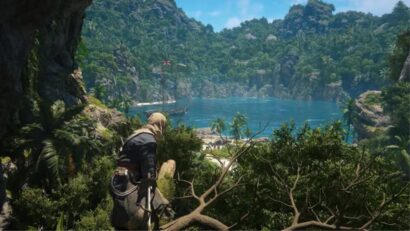 Person in climbing gear on a rocky ledge overlooking a turquoise bay framed by lush tropical cliffs. The scene shows a distant ship on calm blue water.
