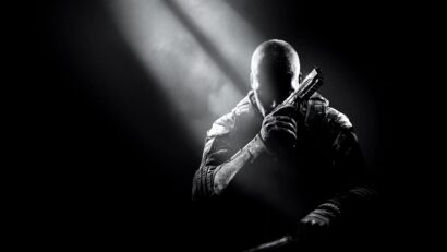 Silhouetted soldier in tactical gear holding a handgun across the chest under a spotlight in a dark scene.