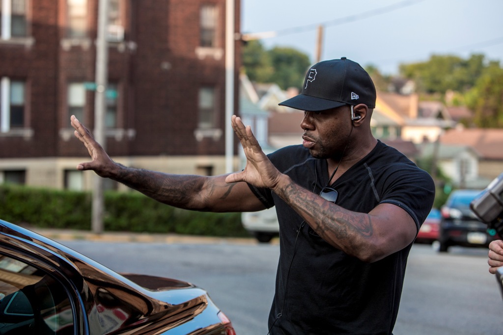 Mv5bmji5mtg0mjmxov5bml5banbnxkftztgwnja5mzuznje v1 Man in a Black T shirt and Cap Directs a Car with Outstretched Arms on a Street Corner