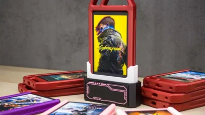 Red plastic flip-top game cartridge case standing upright with a Cyberpunk poster on a yellow background in the center; several red and colored game cartridges lie flat around it on a table.