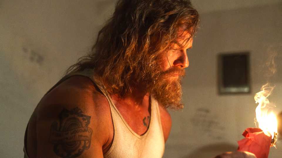 Alan ritchson s john holding a paper burning in motor city نقد و بررسی فیلم سینمایی Motor City | امیدواری کاذب برای مخاطبان | موبوگیم