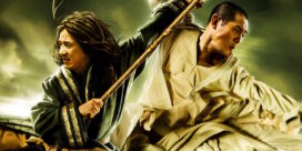 Two martial artists clash in a dynamic duel, one with a wooden staff and flowing robes against a murky green background.