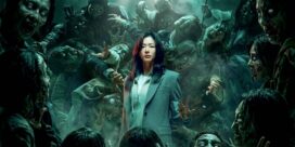 Calm central woman in a teal coat surrounded by advancing zombies in a smoky green-lit scene.