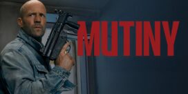 Man in a denim jacket holding a rifle, peering around a doorway with bold red text on a dark wall behind him.