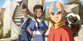 Aang with the blue arrow on his head stands at the front, a lemur on his shoulder, with two friends and a sunlit stone fortress behind them.