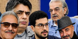 Group of five men posing closely for a selfie, smiling and looking at the camera.