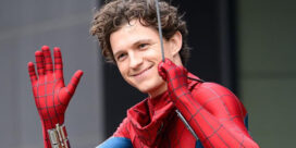 Person in a Spider-Man suit waves and smiles at the camera.